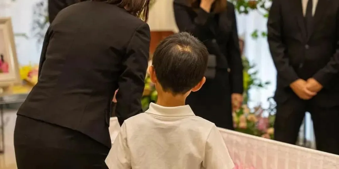 花で飾られた棺のそばで、子どもとご家族が故人を見送る家族葬の写真
