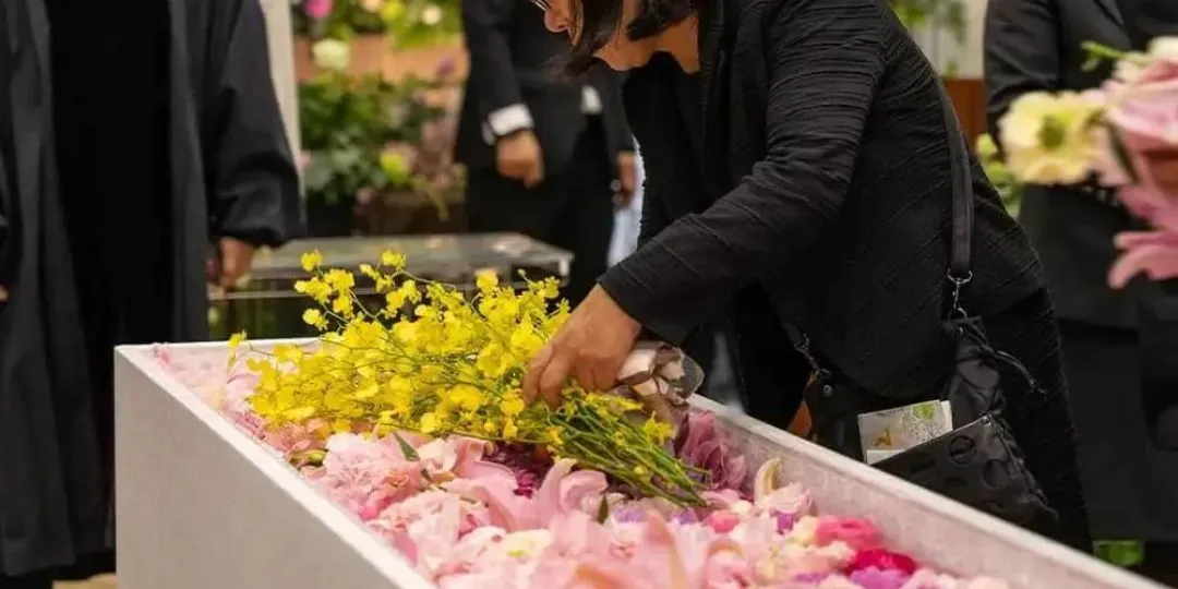 黄色やピンクの花を棺に手向ける、一日葬のお別れの写真